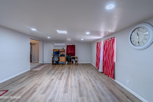 interior space with a wall unit AC, wood finished floors, and baseboards