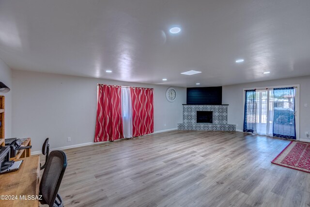 living area featuring baseboards, wood finished floors, and a fireplace