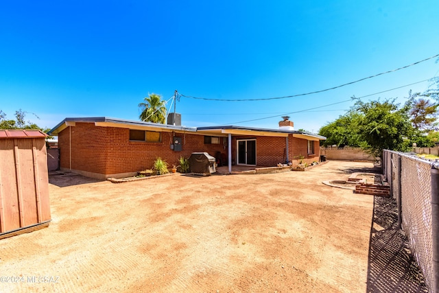 rear view of property featuring an outdoor structure, a fenced backyard, brick siding, and a chimney