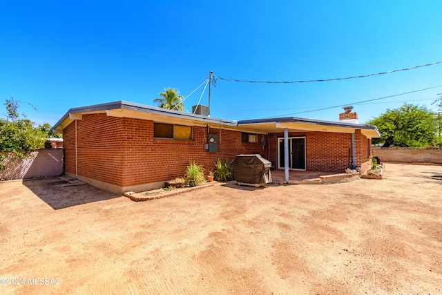 rear view of property featuring brick siding, a patio area, a chimney, and fence