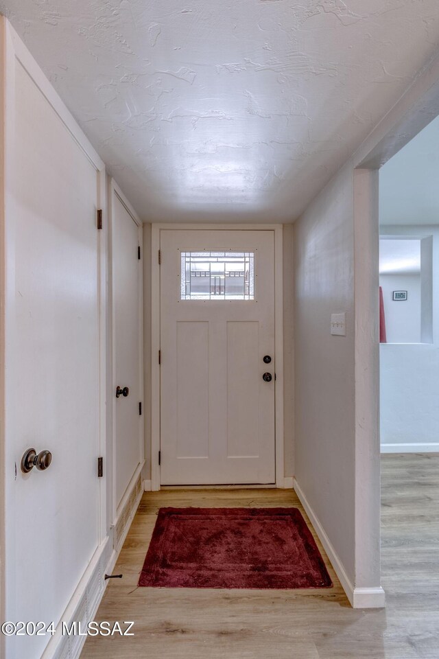 entryway with light wood-type flooring and a textured ceiling