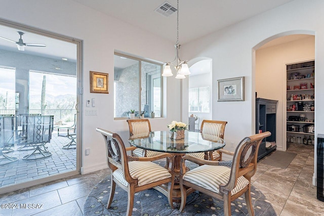 dining room featuring built in shelves and ceiling fan with notable chandelier