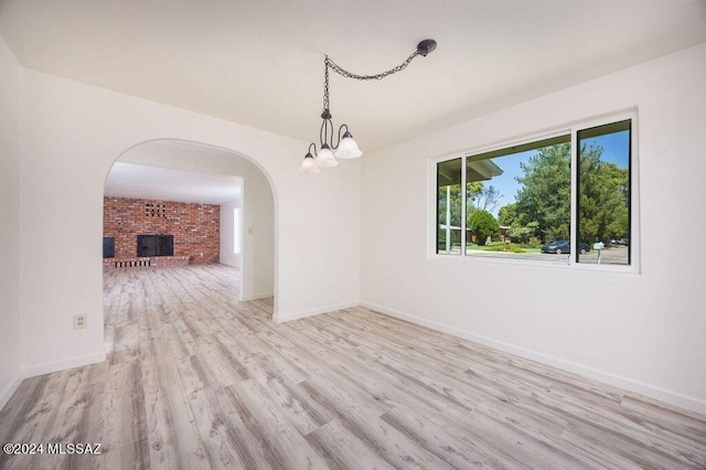 unfurnished dining area with a fireplace and light hardwood / wood-style floors