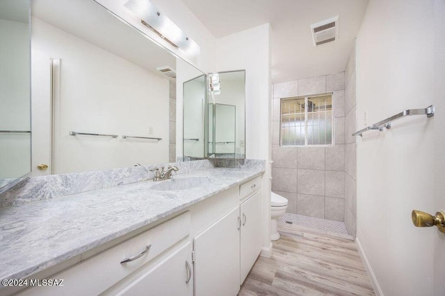 bathroom featuring tile walls, toilet, vanity, and hardwood / wood-style flooring