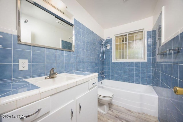 full bathroom featuring hardwood / wood-style flooring, toilet, vanity, and tile walls