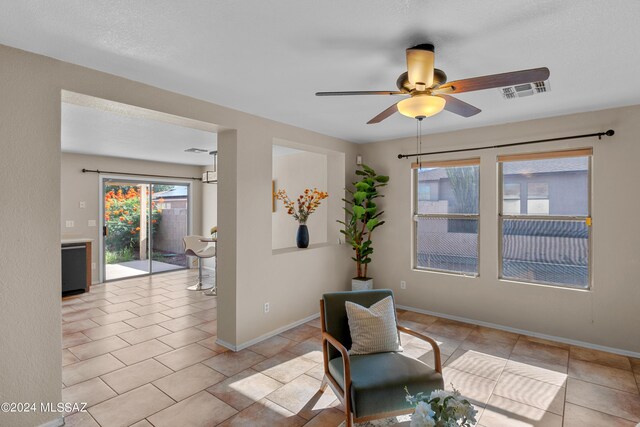 living area with ceiling fan and light tile patterned floors