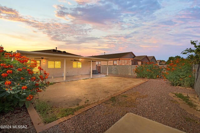 back house at dusk featuring cooling unit and a patio