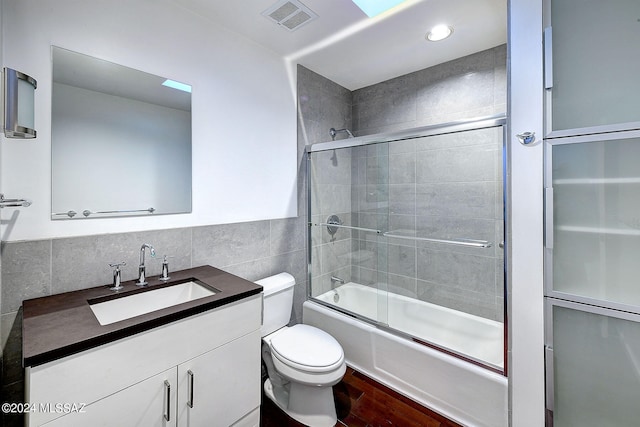 full bathroom with toilet, shower / bath combination with glass door, vanity, wood-type flooring, and tile walls