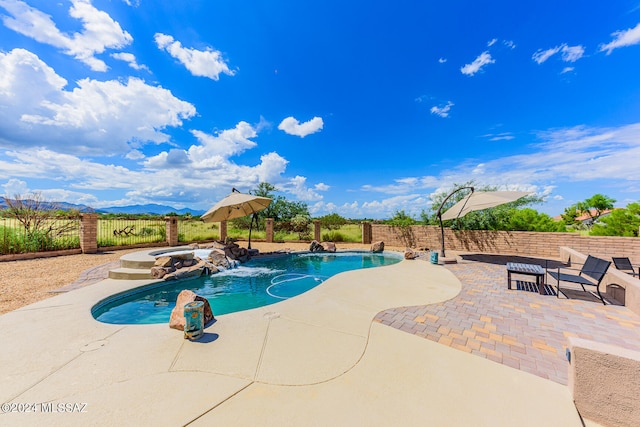 view of pool featuring pool water feature, a patio, a mountain view, and an in ground hot tub