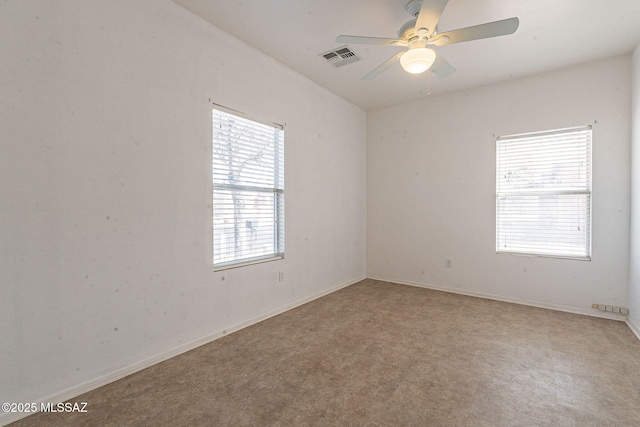 spare room with baseboards, visible vents, and a ceiling fan