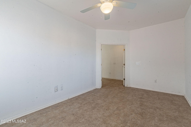 spare room featuring a ceiling fan, light carpet, and baseboards