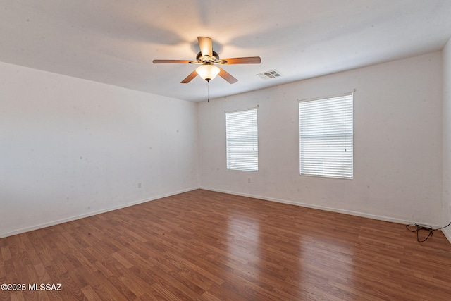 unfurnished room with a ceiling fan, visible vents, baseboards, and wood finished floors