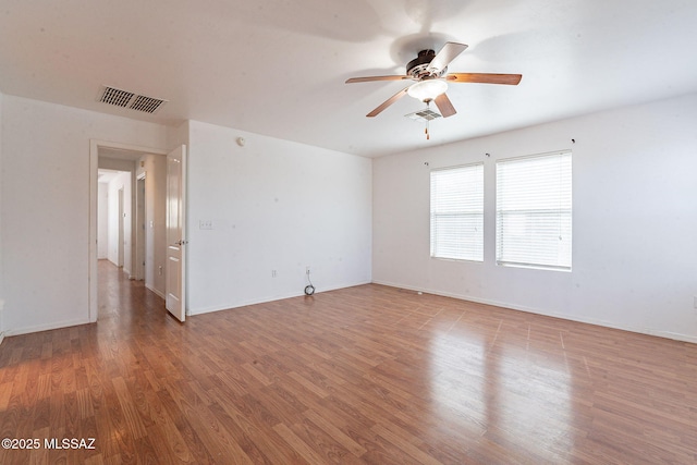 unfurnished room featuring baseboards, wood finished floors, visible vents, and a ceiling fan