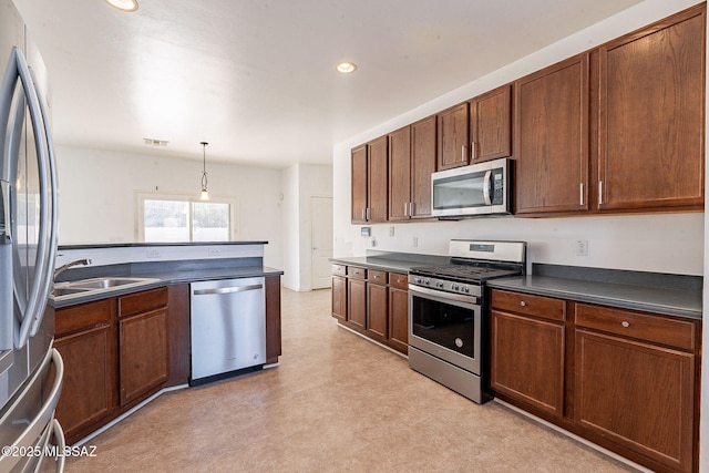 kitchen with dark countertops, decorative light fixtures, stainless steel appliances, light floors, and a sink