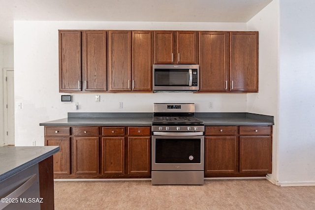 kitchen featuring appliances with stainless steel finishes, dark countertops, and brown cabinets