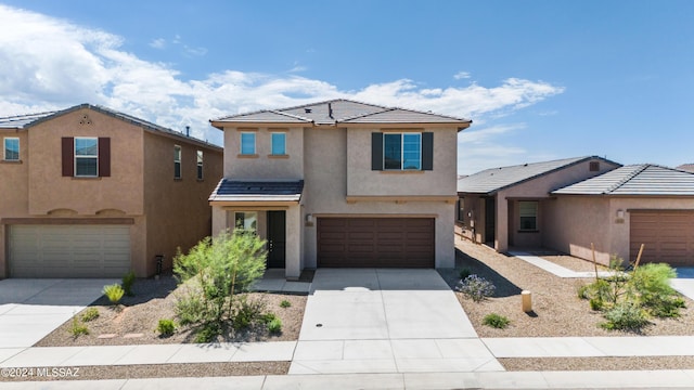 view of front facade featuring a tile roof, driveway, an attached garage, and stucco siding