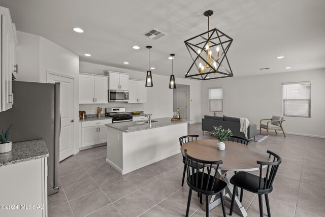 kitchen with light stone countertops, pendant lighting, stainless steel appliances, white cabinets, and light tile patterned flooring