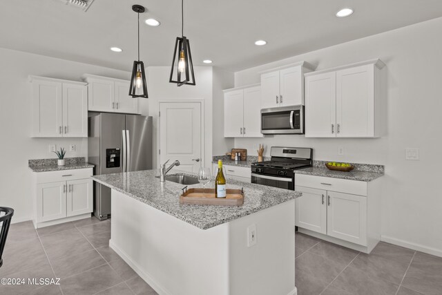 kitchen with white cabinets, appliances with stainless steel finishes, light tile patterned floors, and an island with sink