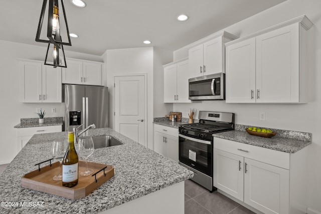 kitchen with pendant lighting, light tile patterned floors, stainless steel appliances, sink, and white cabinets