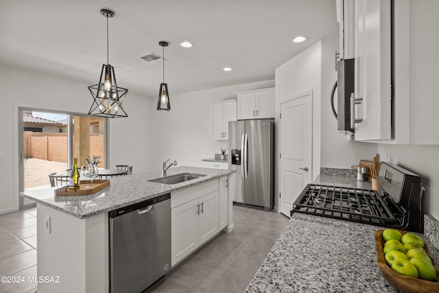 kitchen featuring white cabinetry, light tile patterned floors, sink, appliances with stainless steel finishes, and a center island with sink