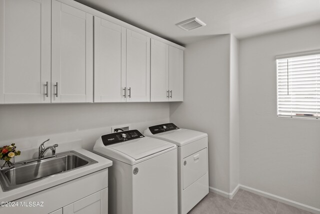 laundry area with light tile patterned floors, cabinets, independent washer and dryer, and sink