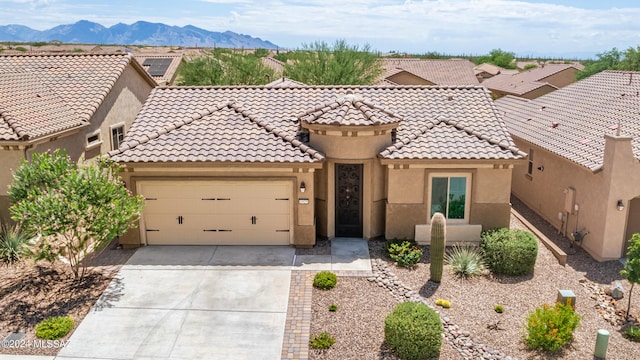 mediterranean / spanish home featuring driveway, a tiled roof, an attached garage, and stucco siding