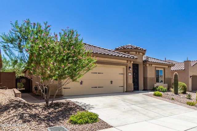 mediterranean / spanish house with a garage, driveway, a tile roof, and stucco siding