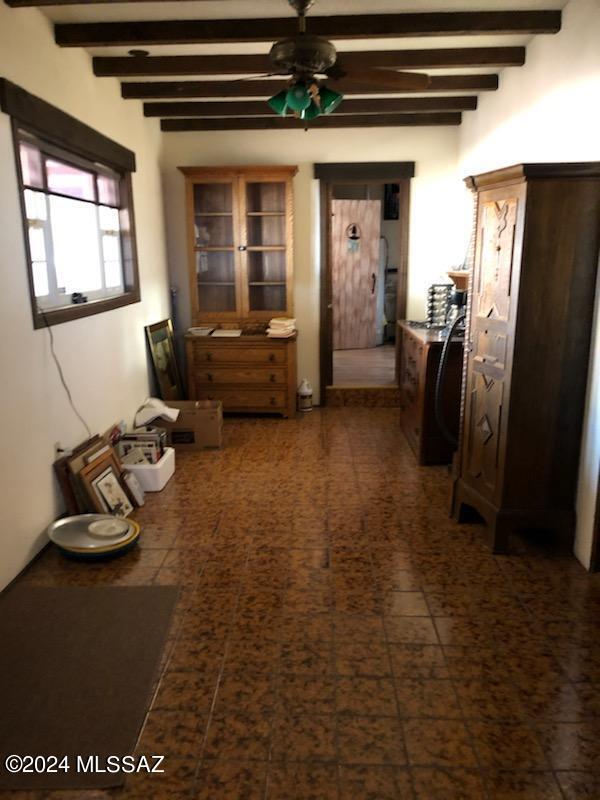 hall featuring dark tile patterned floors and beamed ceiling