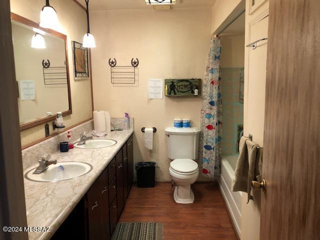 full bathroom with toilet, vanity, shower / bathtub combination with curtain, and wood-type flooring