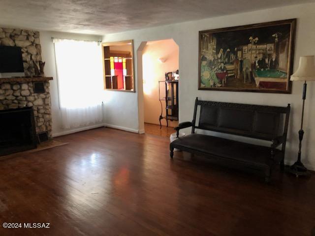 living area featuring a stone fireplace and wood-type flooring