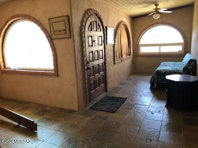 entrance foyer featuring ceiling fan and dark tile patterned flooring