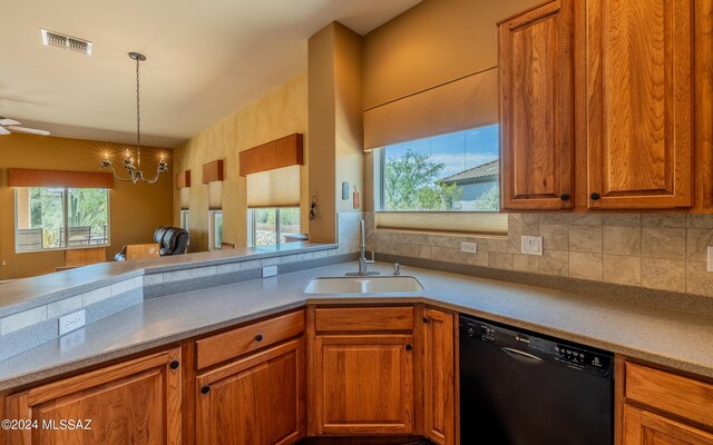 kitchen with backsplash, dishwasher, ceiling fan with notable chandelier, sink, and pendant lighting