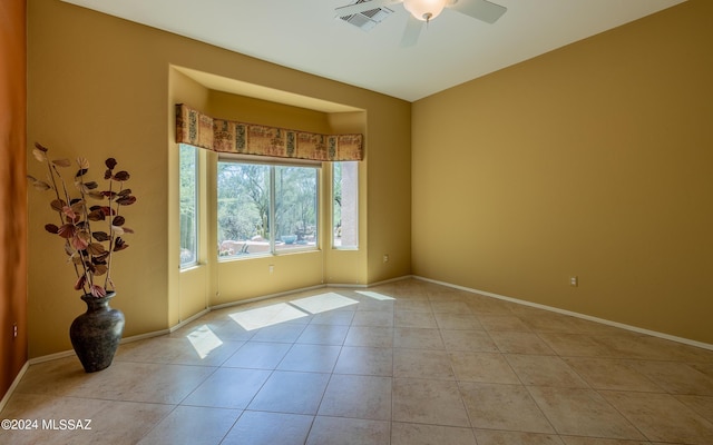 empty room with a ceiling fan, visible vents, baseboards, and tile patterned floors