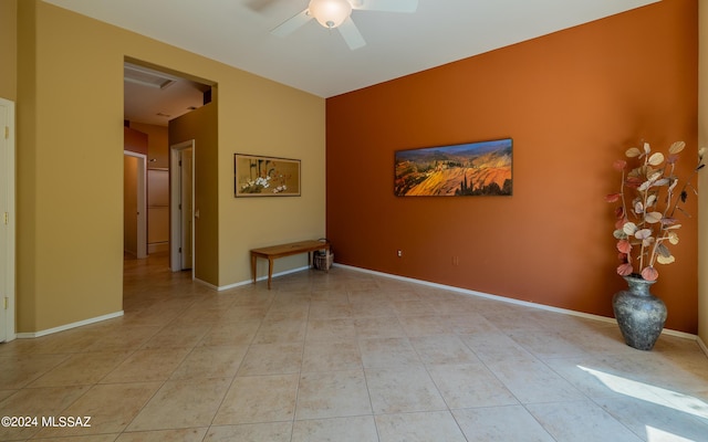 spare room with light tile patterned floors, a ceiling fan, and baseboards