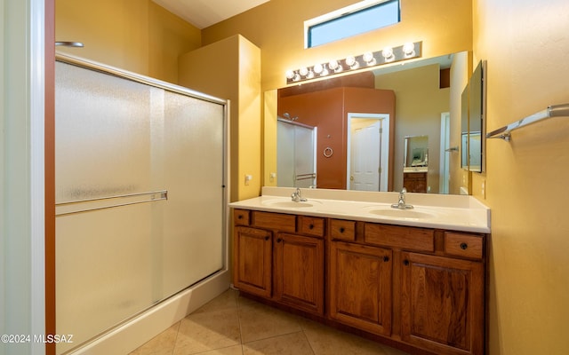 full bath with a shower stall, double vanity, a sink, and tile patterned floors