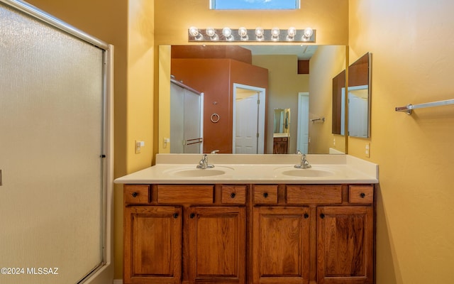 bathroom featuring double vanity, a sink, and a shower with shower door