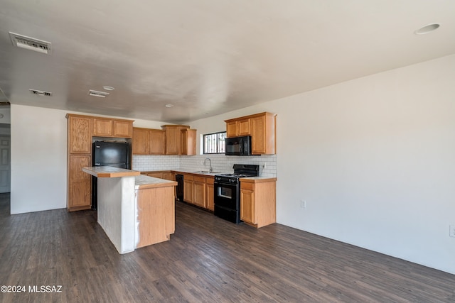 kitchen with black appliances, sink, a center island, decorative backsplash, and dark hardwood / wood-style floors