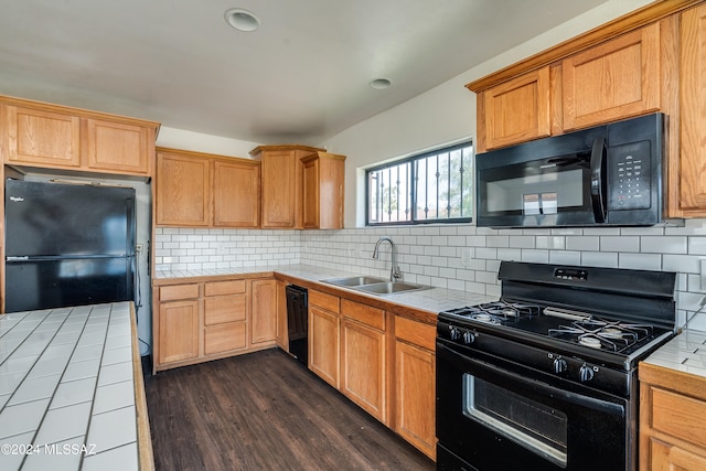 kitchen with tile countertops, sink, black appliances, dark wood-type flooring, and tasteful backsplash