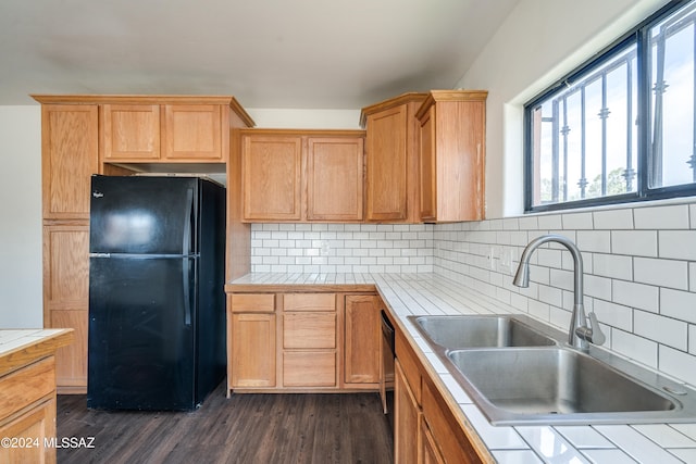 kitchen featuring tile countertops, black refrigerator, dark hardwood / wood-style flooring, and tasteful backsplash