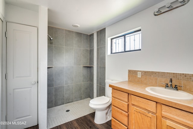 bathroom with vanity, toilet, hardwood / wood-style flooring, and a tile shower