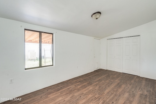 unfurnished bedroom with vaulted ceiling, a closet, and wood-type flooring