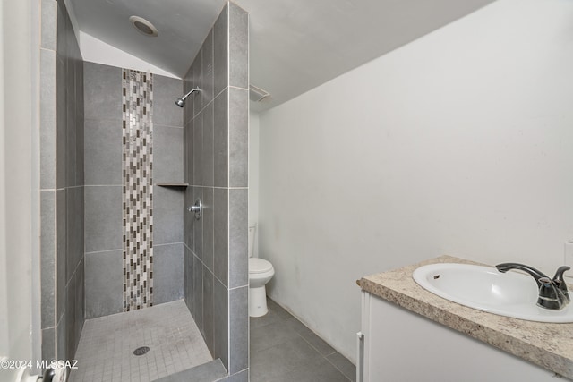 bathroom featuring tile patterned flooring, vanity, toilet, and a tile shower