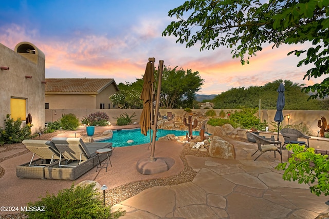 pool at dusk with a patio area