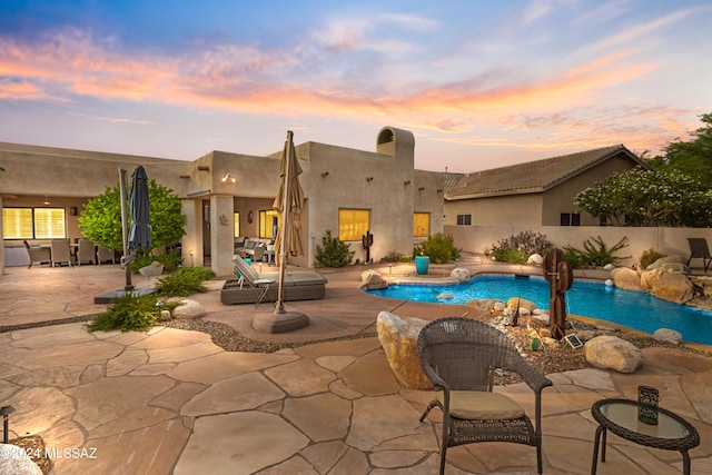 pool at dusk with a patio area