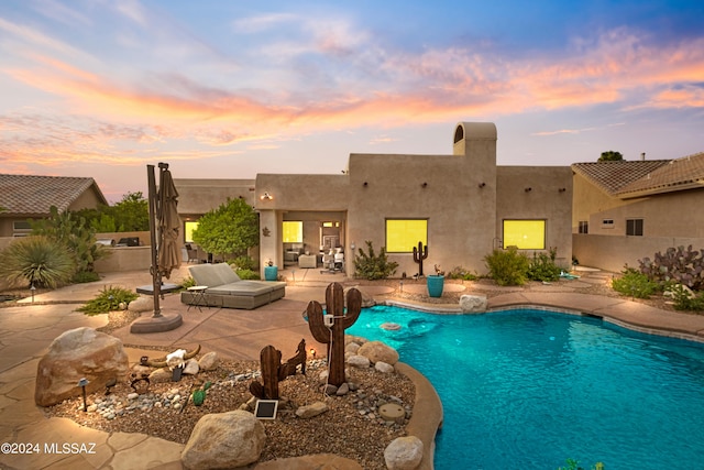 pool at dusk with a patio area