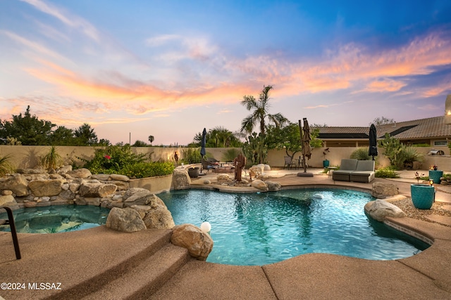 pool at dusk featuring a patio area and pool water feature