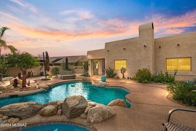 pool at dusk featuring a patio