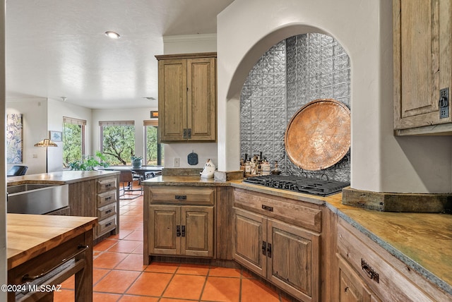 kitchen featuring light tile patterned floors, backsplash, black gas stovetop, crown molding, and wood counters