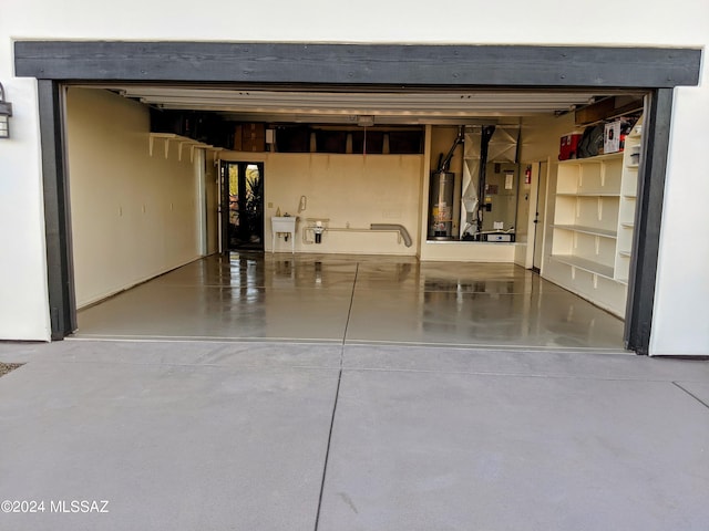 garage with gas water heater, sink, and heating unit