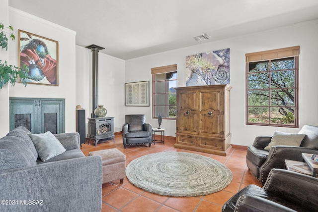 living room with tile patterned flooring, ornamental molding, a wealth of natural light, and a wood stove